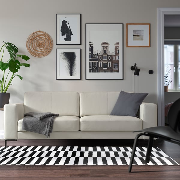 Witte leren bank, zwart & wit tapijt, kunst, lamp, plant.