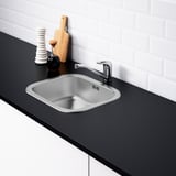 Moderne spoelbak in RVS met geluidsabsorberend materiaal, gemonteerd in zwart aanrechtblad. Chromen kraan inbegrepen.
