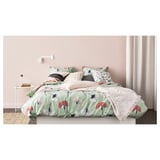 Bed met groen bloemendekbed, beige gordijnen, nachtkastjes en wandlampje.
