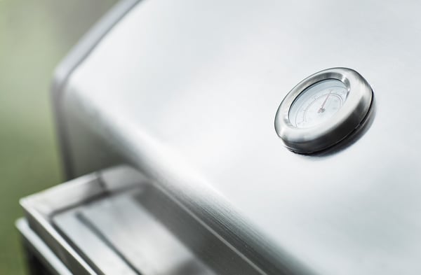 Oventhermometer op zilverkachel. Ronde wijzerplaat, naald, moderne keuken.