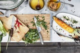 GRILLSKÄR kookeiland, zilver, roestvrijstalen blad, rechthoekig, chromen handgrepen, twee houten planken, geprepareerde grillmaïs, messen, kruiden.