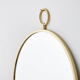 Ronde spiegel met gouden lijst hangt stevig aan de muur. Helder, reflecterend oppervlak, elegante messing details.