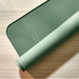 Groene siliconen placemat met kattenoren op houten tafel. Beschermt oppervlakken tegen morsen en krassen.