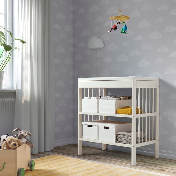 Kinderkamer met witte GULLIVER commode, muur met wolkenpatroon en knuffels.