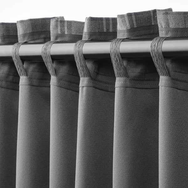 Close-up van HÄGGVECKMAL gordijnen met donkergrijs tartanpatroon en luszakken voor het inbrengen van de gordijnroede.