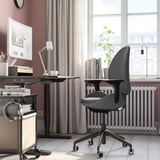 Modern rood thuiskantoor met HATTEFJÄLL stoel, bureau, monitor en accessoires, met de nadruk op comfort en professionele opstelling.