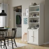Moderne keuken met witte HAUGA kasten, verstelbare planken, zwarte stoelen, hardhouten vloer, grijze wanden en hanglamp.