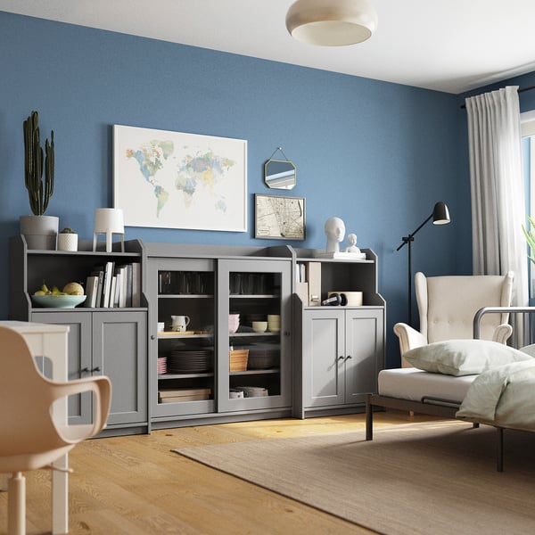 Eigentijdse leefruimte met blauwe muren, grijze HAUGA opbergmeubels, witte plattegrond, cactus en een beige stoel.