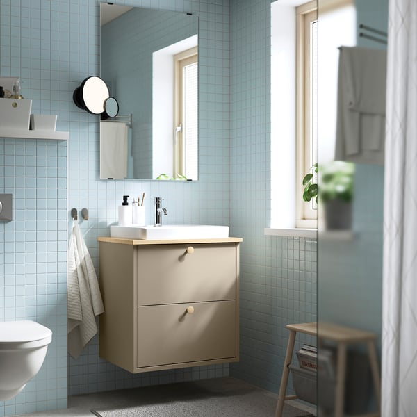 Moderne badkamer met lichtblauwe tegels, HAVBÄCK wastafel, wastafel, spiegellampen, gedeeltelijk toilet, kruk met tijdschrift, raam, douchegordijn.