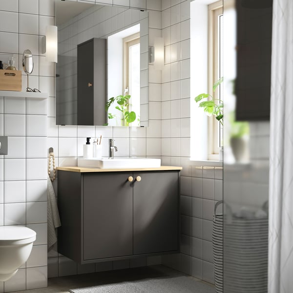 Badkamer met grijze kaptafel, houten aanrecht, witte wastafel, planten, lampen