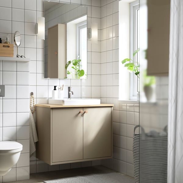 Moderne badkamer met beige HAVBÄCK kaptafel, dubbele deuren, licht aanrecht, spiegel en natuurlijk licht.
