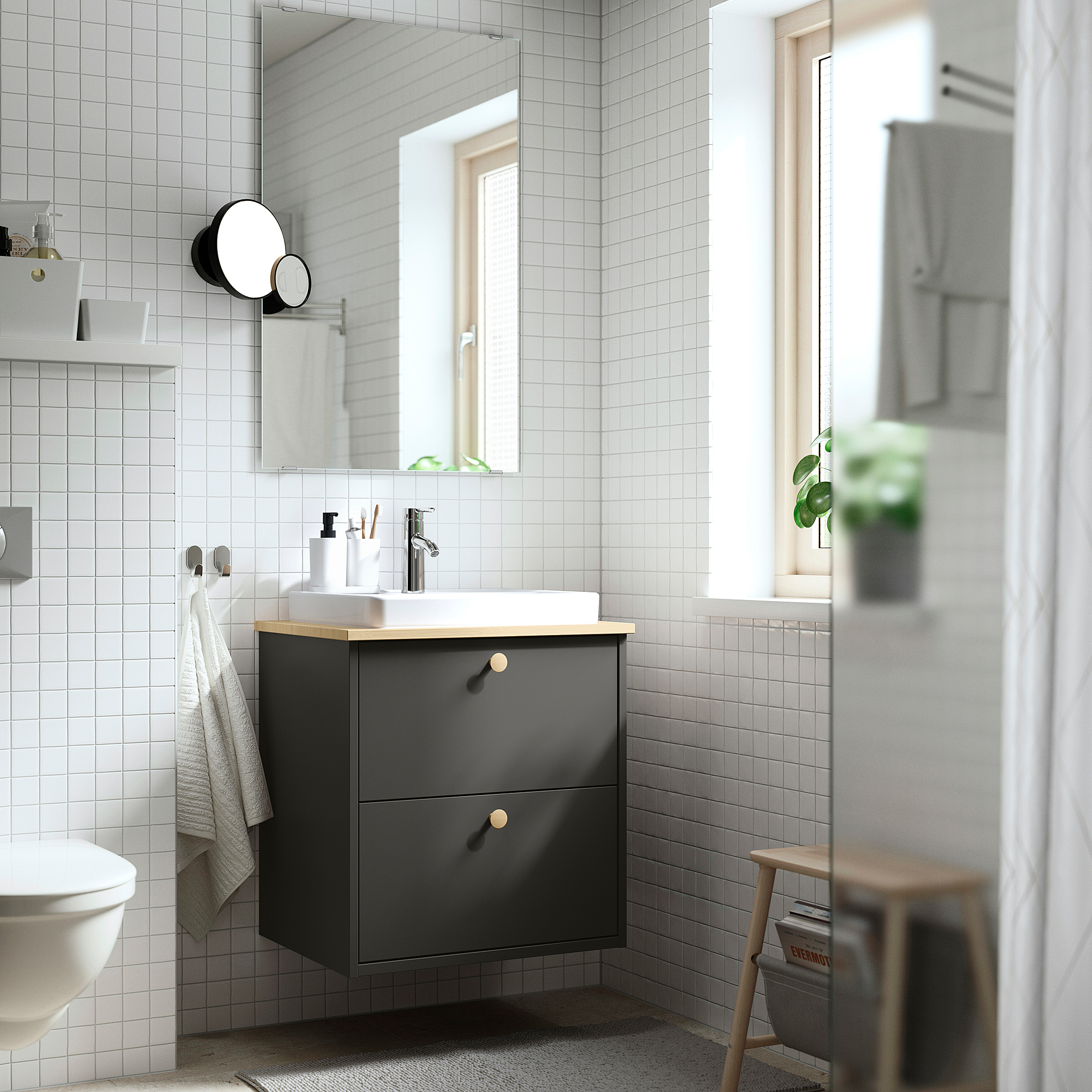 Moderne badkamer: donkergrijze badmeubel, spiegelkast, toilet, raam, krukje met tijdschrift, witte tegels, zwart-wit licht.