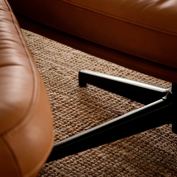 Bruine lederen fauteuil close-up, met premium stiksels en textuurdetails.