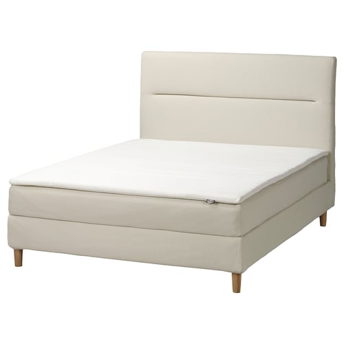 Modern wit gestoffeerd bed met houten poten en gewatteerd hoofdeinde.