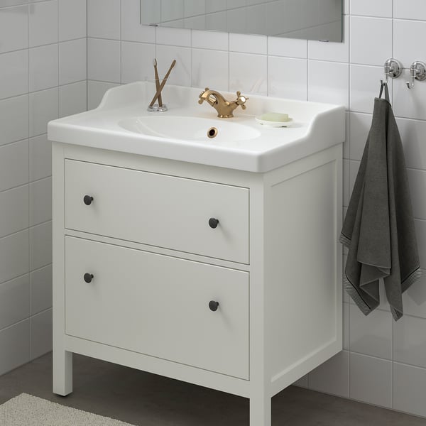 HEMNES witte wastafel, gouden kraan, zwarte handgrepen, grijze handdoek.