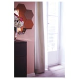 Zeshoekige oranje spiegels op roze muur dichtbij venster met wit gordijn.