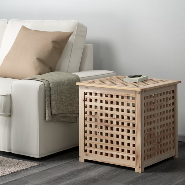 De houten HOL bijzettafel met roostermotief staat naast een witte bank en laat zijn kleine formaat en praktische opbergruimte zien.