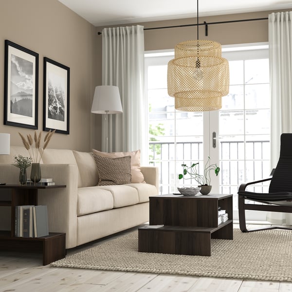 Minimalistische woonkamer met beige bank, houten salontafel, zwarte fauteuil, groot raam en hanglamp. Beige muren en neutraal vloerkleed.