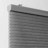 Grijze honingraatjaloezieën gemonteerd aan de muur, met celmateriaal voor isolatie en lichtblokkering.