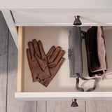 Bruine leerhandschoenen op witte plank met paraplu en jas.