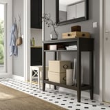 IDANÄS houten consoletafel met planken tegen de muur, met decorartikelen, boeken en mand.