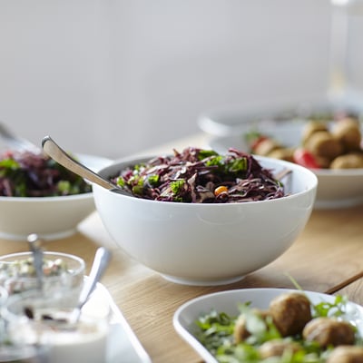Kommen salade op houten tafel; IKEA bakken netjes gestapeld.