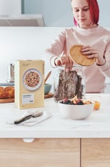 Vrouw giet ontbijtgranen in ikea-thema keuken.