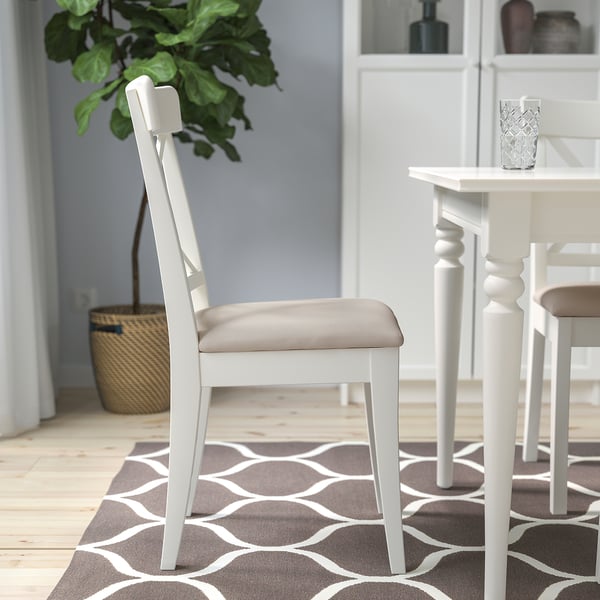 Witte houten stoel met beige gewatteerde zitting, onderdeel van de INGOLF-serie, ideaal om comfortabel te eten en te kletsen.