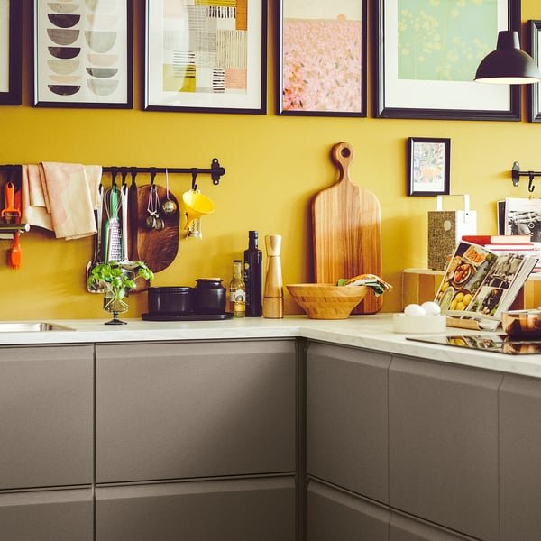 Gele keuken met grijze kasten, kookgerei en aanrechtartikelen.