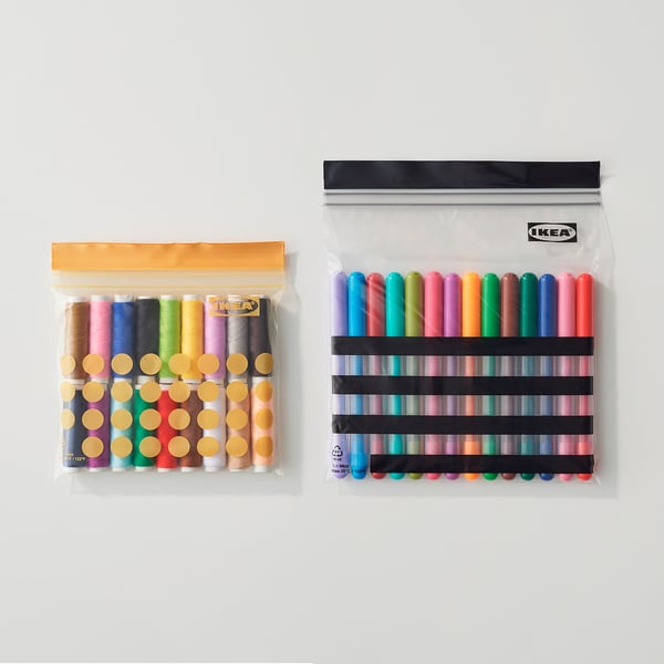 Twee doorzichtige hersluitbare plastic zakken van IKEA, de ene met kleurrijke garens, de andere met stiften, die de organisatie en opslagmogelijkheden laten zien.