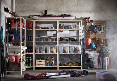 Garage met IVAR houten planken gevuld met sportuitrusting, helmen en outdooruitrusting.
