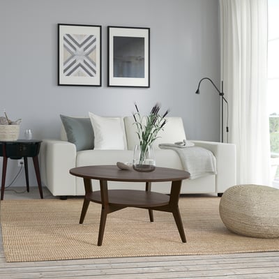 Moderne woonkamer met JAKOBSFORS salontafel, bloemen en kunst aan de muur.