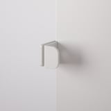 Wit metalen deurscharnier gemonteerd op muurhoek, minimalistisch design.