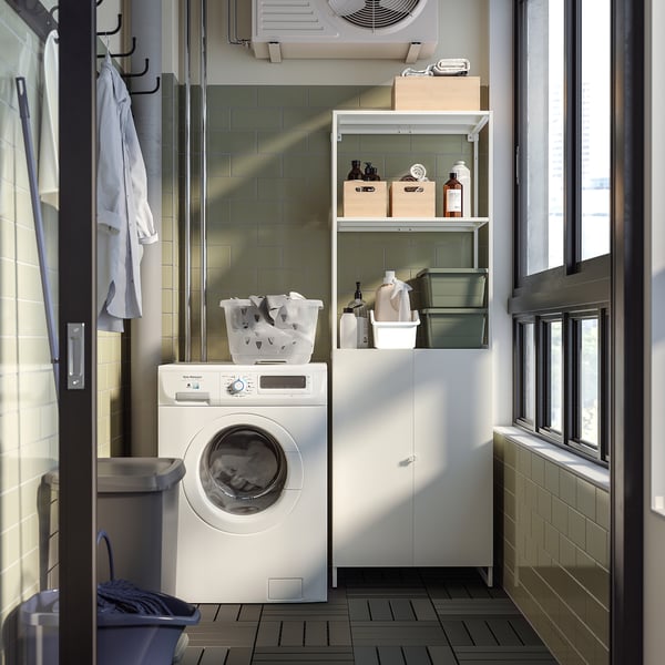 Compacte wasruimte met witte wasmachine, opbergplanken met schoonmaakspullen en het drogen van kleding.