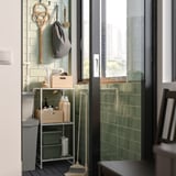 Groen betegeld balkon met JOSTEIN opbergplank, ophanggereedschap en schoonmaakspullen.