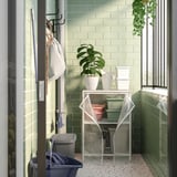 Klein, groen betegeld balkon JOSTEIN witmetalen rekken met plant, emmers en wasgoed.