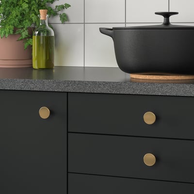 Moderne keuken met zwarte kasten, gouden knoppen en olijfolie.