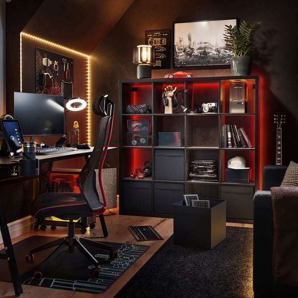 Modern thuiskantoor met KALLAX zwarte rekken, rode lichten, computerbureau, stoel, gitaar en decor.
