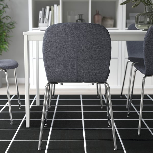 Moderne zwarte stoelen met chromen poten voor een wit bureau op een geruite vloer voor kantoor of thuiswerkruimte.