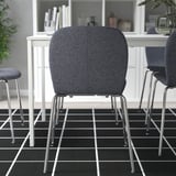 Moderne zwarte stoelen met chromen poten voor een wit bureau op een geruite vloer voor kantoor of thuiswerkruimte.