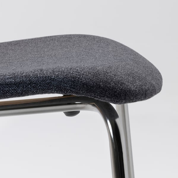 Close-up van moderne gestoffeerde stoel, met een slank verchroomd metalen frame en donkergrijze geweven stof.