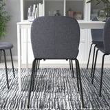Donkere gestoffeerde bureaustoel met metalen poten op een gedessineerd tapijt, in een kamer met witte meubels.