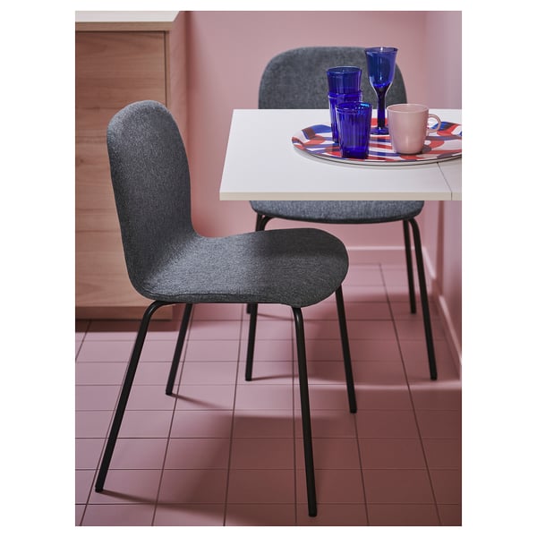 Moderne eetopstelling met twee grijze KARLPETTER stoelen en een witte tafel, met blauw en roze serviesgoed.