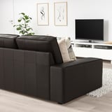 Moderne woonkamer met grote KIVIK zwarte leren bank, geometrische kussens, flatscreen-tv en abstracte kunst aan de muur.