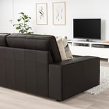 Moderne woonkamer met grote zwarte leren KIVIK bank, wit tv-meubel en abstracte kunst aan de muur. De grootte van de banken domineert de ruimte.