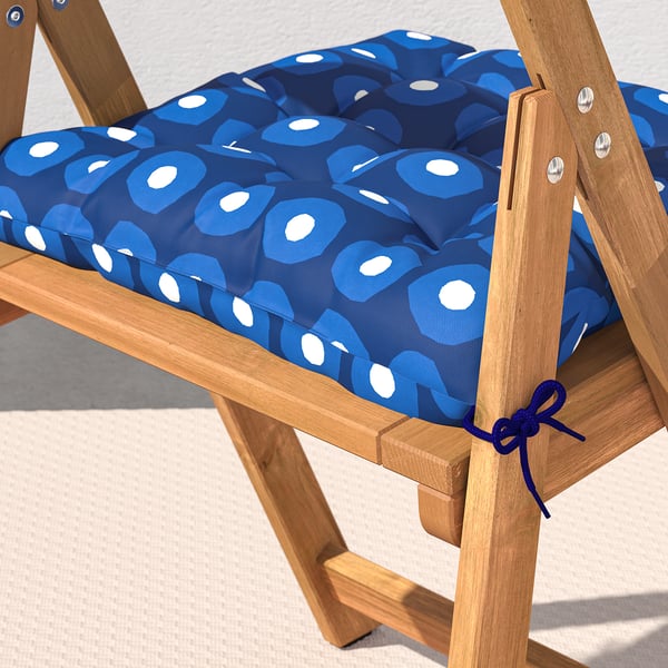 Een houten klapstoel met een kussen met een blauw patroon dat met banden is vastgezet.