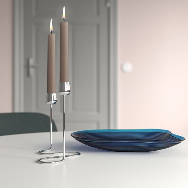 Zilveren kandelaar met beige kaarsen en spiraalvoet op tafel naast donkerblauwe glasplaat.