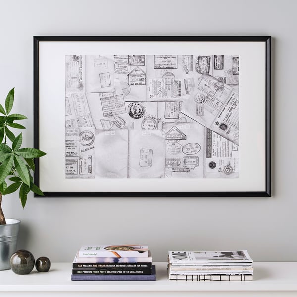Ingelijste collagekunst met paspoortstempels die op een plank worden getoond, vergezeld van boeken en een plant.