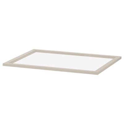 Een KOMPLEMENT glazen plank in beige. Het heeft een rechthoekige vorm met een frame van vezelplaat en een centrum van gehard glas, ontworpen voor het opbergen van kledingkasten.