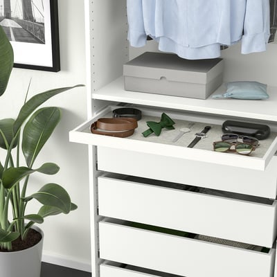 Witte kledingkast met accessoire lade, lades en plant ernaast.